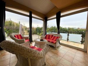 a screened in porch with chairs and tables and windows at Villa au calme tout confort in Lapalud