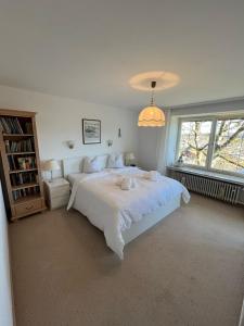 ein weißes Schlafzimmer mit einem großen Bett und einem Fenster in der Unterkunft Ferienwohnung Sonnenaufgang Bad Tölz in Bad Tölz