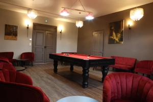 Cette chambre comprend une table de billard et des chaises rouges. dans l'établissement Château de Petit Bois, à Cosne-dʼAllier
