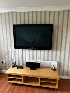 a flat screen tv on a wall with a coffee table at Modern 5 Bedroom House in Willesborough