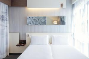 una camera con un letto bianco e una grande finestra di Ibis Styles Roma Eur a Roma Altre 37 foto