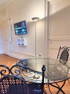 a glass table with two chairs and a television on a wall at Grand studio 38m2 dans ancien palace avec piscine et place de parking privée in Aix-les-Bains