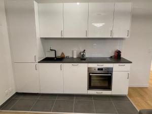a white kitchen with white cabinets and a sink at Appartement Saint ouen proche stade de france in Saint-Ouen