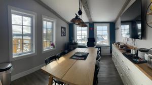 a dining room with a long wooden table and windows at Bumblebee Bight Inn in Pilleyʼs Island