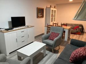 sala de estar con sofá y TV en Apartamento Turístico Cervantes 18, en Losar de la Vera