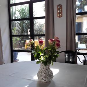 a vase with flowers on a table with a window at SOUS LE NEFLIER in Nîmes