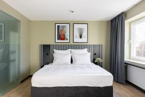 a bedroom with a large bed and two windows at numa I Bona Rooms & Apartments in Bonn