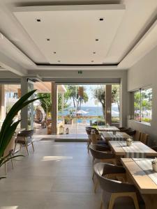 a restaurant with tables and chairs and large windows at Aroma Beach Hotel Bungalows in Limenas