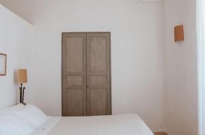 una camera con letto bianco e armadio in legno di Masseria Li Foggi a Gallipoli