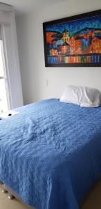 馬尼薩萊斯的住宿－Robles10 El Cable Luxury Highrise，卧室内的一张蓝色的床,墙上挂着一幅画