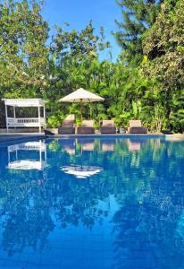a swimming pool with chairs and an umbrella at CASA BALI Juan Dolio Beach in Juan Dolio