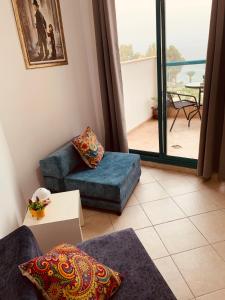 uma sala de estar com um sofá azul e uma varanda em טבריה em Tiberíades