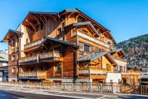 Un grand bâtiment en bois avec balcon se trouve dans une rue. dans l'établissement MAS JOUX PLANE 102, à Morzine