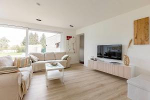 een woonkamer met een bank en een tv bij Maison Mathieu - vakantiewoning 8p in Bilzen
