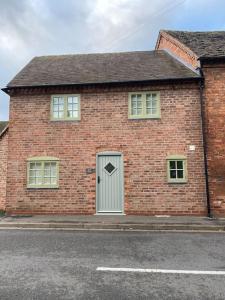 una casa de ladrillo con una puerta gris y ventanas en The Snug Entire home Sleeps 2, Stratford upon Avon, en Shottery