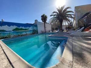 una piscina con agua azul y palmeras en Hotel Los Aromos en Mina Clavero