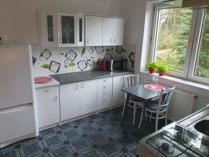 uma cozinha com armários brancos, uma mesa e uma janela em Przestronny, komfortowy dom em Swornegacie