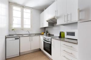 a white kitchen with white cabinets and a window at Sagrada Familia IV by Enjoy Apartments in Barcelona