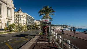 un arrêt de bus dans une rue de la ville avec un palmier dans l'établissement Guest House Maccarani, à Nice