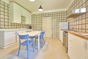 a kitchen with a white table and blue chairs at Villa Elle Exclusive Isola d'Elba in Capoliveri