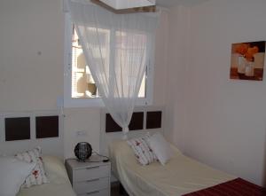 1 dormitorio con 2 camas y una ventana con cortinas en Coll Verd Apartment, en Denia