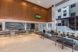 a lobby of a building with people sitting at tables at The Charm Resort Phuket - SHA Certified in Patong Beach