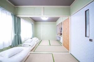 een kamer met een rij witte bedden bij Otaru Shikkui Cottage in Kita-hamachō
