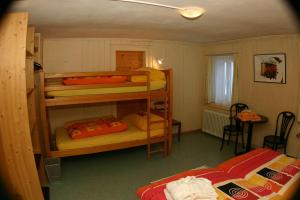 Zimmer mit 2 Etagenbetten und einem Tisch mit einem Stuhl in der Unterkunft Landgasthaus Post in Surava
