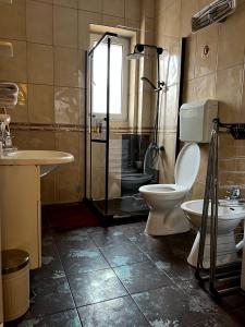 uma casa de banho com um WC, um chuveiro e um lavatório. em Light and Bright Central em Pristina