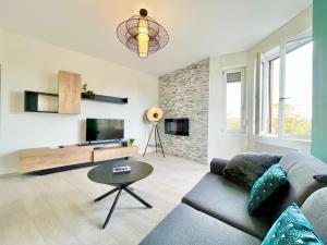 uma sala de estar com um sofá e uma mesa em COLMAR - Appartements Deluxe - Lumineux - Stationnement Gratuit et Facile dans la rue em Colmar