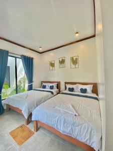 two beds in a bedroom with blue curtains at Kampot River Bungalow by MAMA in Kampot