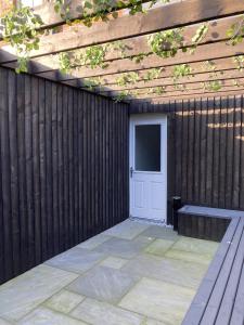 a wooden fence with a white door and a bench at Vibe Holiday Apartments in Blackpool