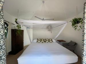 a bedroom with a white bed with a canopy at Quinta Feliz Troncones in Troncones