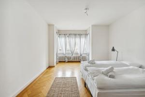a white room with two beds and a rug at Central Apartment for City Explorers 224 in Zurich