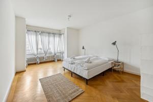 ein weißes Schlafzimmer mit einem Bett und Holzboden in der Unterkunft Central Apartment for City Explorers 224 in Zürich
