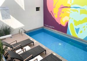 a swimming pool with chairs and a painting on the wall at The Andy Hotel in Querétaro