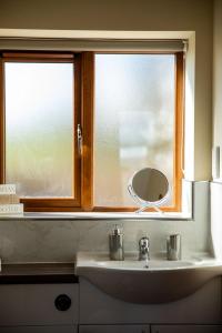 a bathroom sink with a mirror and a window at Pentre Fach in Llanddewi Ystradenny