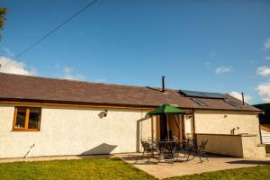 a house with a table and chairs and a green umbrella at Pentre Fach in Llanddewi Ystradenny