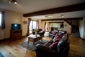 sala de estar con sofá de cuero y TV en Pentre Fawr en Llanddewi Ystradenny