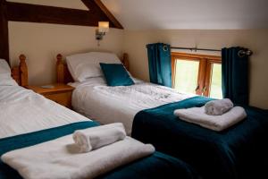 1 dormitorio con 2 camas y toallas. en Pentre Fawr en Llanddewi Ystradenny