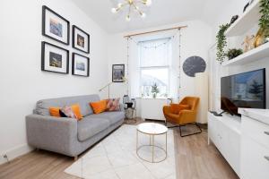 uma sala de estar com um sofá e uma televisão em JOIVY Bright 2 bed flat, sleeps 6, next to Holyrood Park em Edinburgo