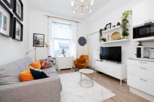 uma sala de estar com um sofá e uma televisão em JOIVY Bright 2 bed flat, sleeps 6, next to Holyrood Park em Edinburgo