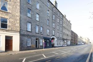 eine leere Stadtstraße mit einem großen Backsteingebäude in der Unterkunft ALTIDO Bright 2 bed flat, sleeps 6, next to Holyrood Park in Edinburgh