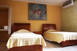 a bedroom with two beds and a painting on the wall at Canal Inn B&B Panama in Panama City