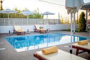a swimming pool with chairs and umbrellas next to it at Seabreeze Villa - with Jacuzzi & heated pool in Mastihari