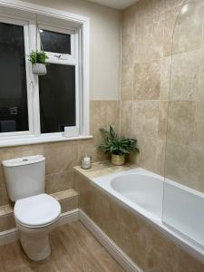 a bathroom with a toilet and a tub and a window at No 12 - Stylish & homely 3 bed with parking close to city centre in Bath