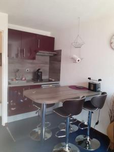 a kitchen with a wooden table and two bar stools at Joli studio proche des telecabines in Uvernet