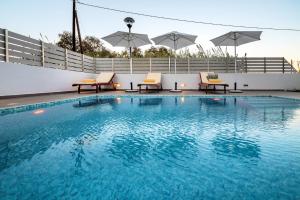 una piscina con sillas y sombrillas en un edificio en Seabreeze Villa - with Jacuzzi & heated pool, en Mastichari