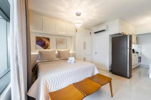 a bedroom with a bed and a refrigerator at 4 Studios Luxo Varanda Cozinha Equipada Piscina Academia Garagem WiFi Perto do Metrô Praça da República São Paulo in São Paulo