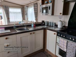 a kitchen with a sink and a stove at 149 Holiday Resort Unity 3 bedroom passes included in Brean